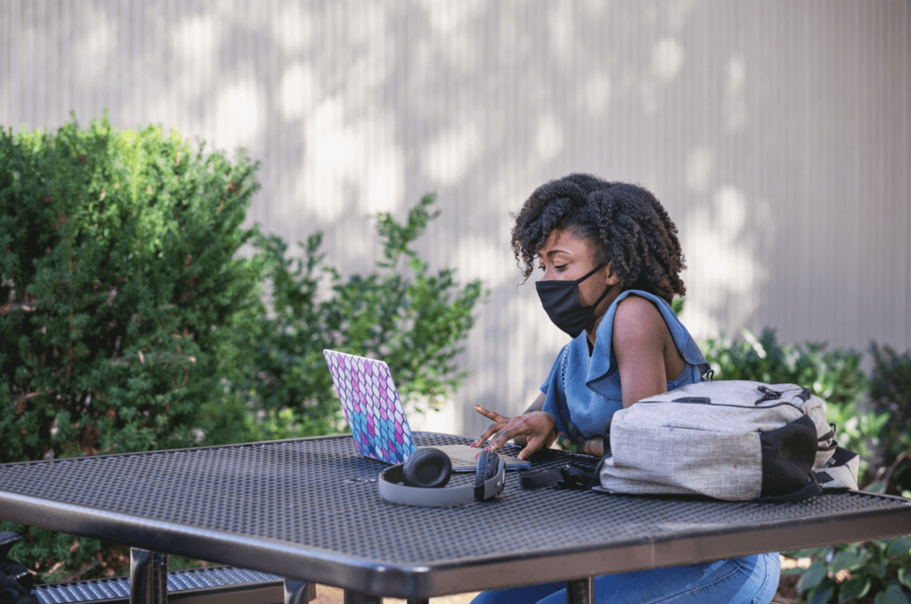 female student. with black face mask on sitting at outside table