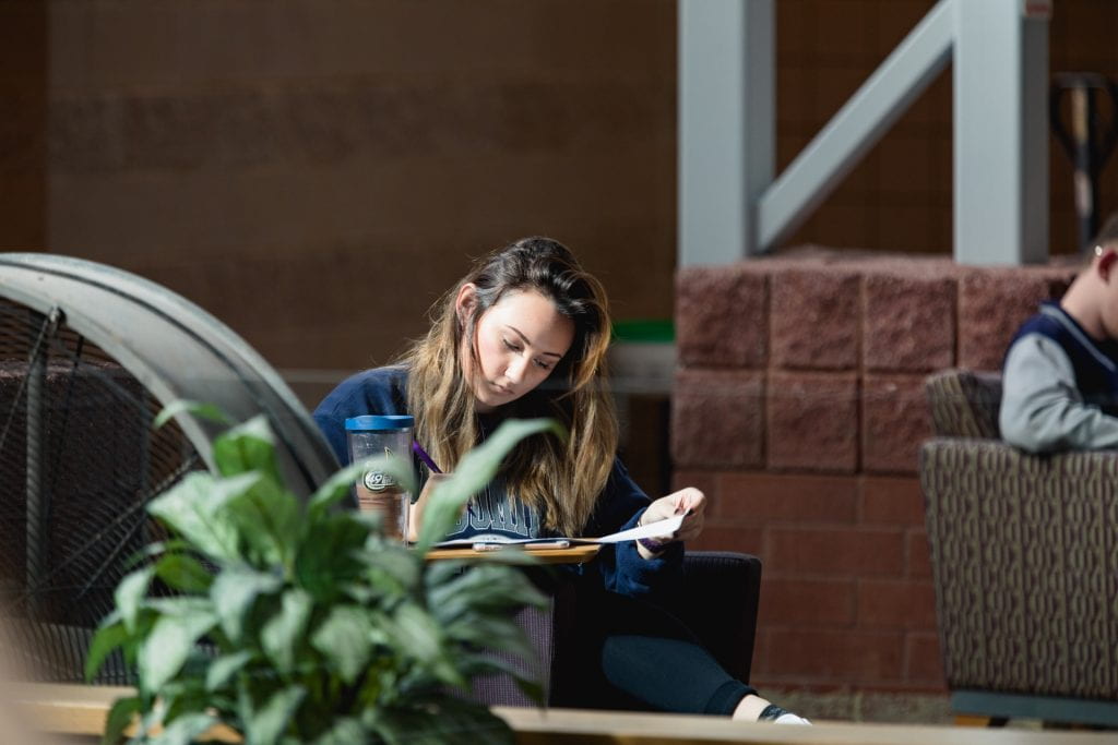 student sitting alone reading a book on Levine Campus