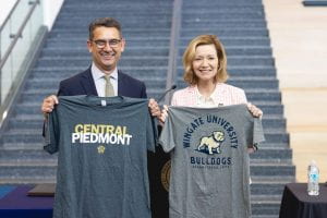 Wingate University president smiling and holding a Central Piedmont t-shirt and Central Piedmont president smiling and holding a Wingate t-shirt.