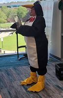 Librarian Cheryl Cole in a penguin suit with a red bow tie, hood with beak, and full penguin feet 