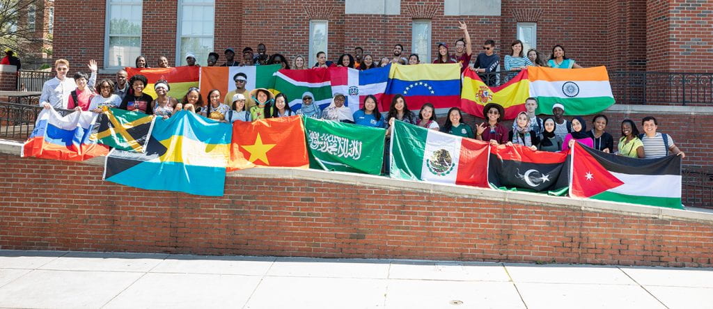large group of students holding flags from various countries
