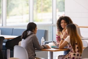 Three students sit around a table talking