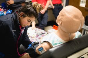 Student in EMT program takes the blood pressure of a medical mannequin.