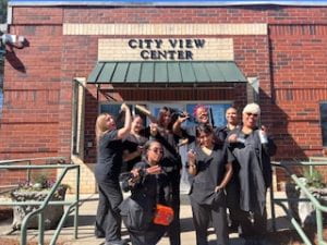 Cosmetology students in uniform pose casually outside of the City View Center