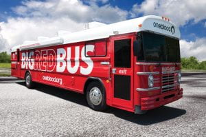 The OneBlood "big red bus" to donate blood, sitting in a parking lot with a blue sky in the background