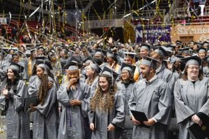 The graduates react to the silver and gold streamers falling over their heads at graduation