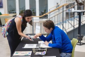 Employee helps student at an information table.