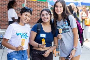 Three smiling students hold fancy popsicles.