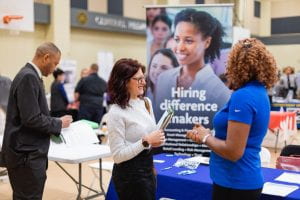 Students at a business and career fair talk with employers.
